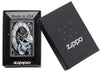 Zippo-aansteker zwarte klok waaruit een doodshoofd tevoorschijn komt met tandwielen op de achtergrond in open geschenkdoos